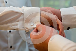 A groom putting on cuff-links. Groom's suit. Close-up