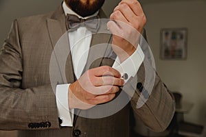 A groom putting on cuff-links. Groom's suit