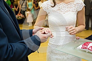 Groom putting golden ring on bride's finger during wedding cerem