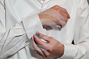 Groom putting on his cufflinks