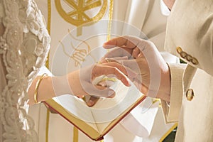 Groom putting ring on bride during religious ceremony