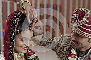 Groom putting Sindoor on Bride's forehead in Indian Hindu wedding. photo