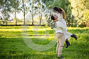 The groom raised and spins bride. Newlyweds kissing. On background on nature in the courtyard of house. Close up