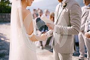 Groom reads an vow from the card to the bride, holding her hand