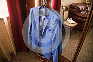 The groom`s blue jacket on a hanger on a vintage wardrobe. Groom`s morning, wedding details, preparation for the wedding ceremon