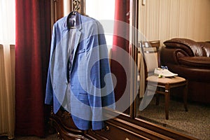The groom`s blue jacket on a hanger on a vintage wardrobe. Groom`s morning, wedding details, preparation for the wedding ceremon