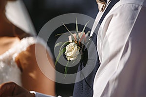 Groom`s boutonniere of white roses, flower on the groom`s jacket