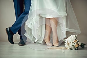 the groom& x27;s feet in boots and the bride& x27;s feet in high-heeled shoes next to the wedding bouquet