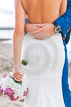 The groom `s hand hug the bride on the beach