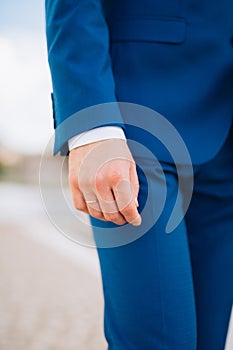 The groom`s hand with a ring on his finger. The groom in a blue