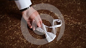 Groom`s hand takes a bow tie. Preparing to wedding day. The man takes the bow-tie. Wedding accessories. Groom holding