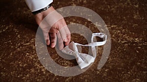 Groom`s hand takes a bow tie. Preparing to wedding day. The man takes the bow-tie. Wedding accessories. Groom holding