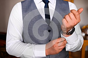 Groom`s morning, details and husband`s meeting on the wedding day. The man fastens a button on the sleeve of his shirt
