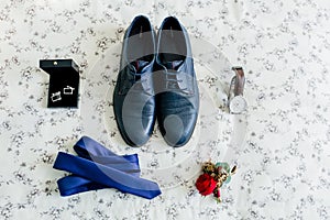 Groom`s shoes and cufflinks, blue tie, wristwatch, boutonniere on a light background. Wedding concept. photo