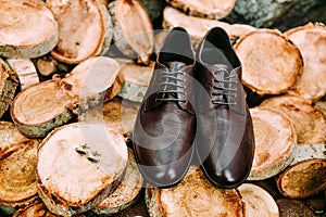 Groom`s shoes and cufflinks on a wooden background. Men`s accessories.