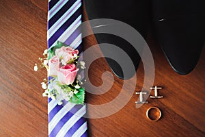 Groom`s wedding details, rings, perfume, tie, boutonniere