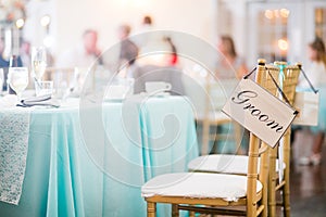 Groom sign hanging from chair at a wedding reception