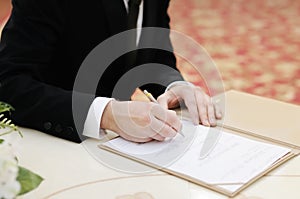 Groom signing marriage license or wedding contract