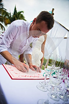 Groom signs documents on registration of marriage in the open air. A young couple signs the wedding documents. Man signs docum