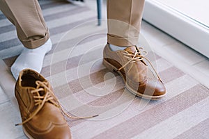 Groom sits on a chair in unlaced shoes. Close-up