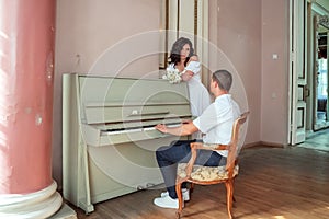 The groom sits at the piano and plays the bride