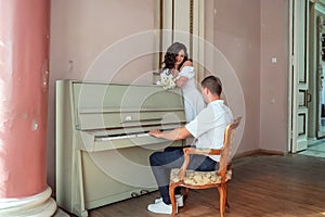 The groom sits at the piano and plays the bride a melody