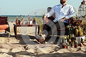 Groom sitting on the chair on the beach