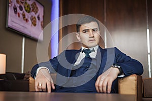 Groom sitting on the leather chair in hotel