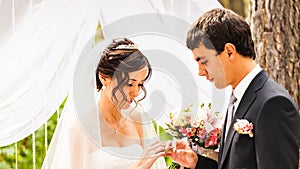 Groom slipping ring on finger of bride at wedding