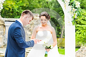 Groom slipping ring on finger of bride at wedding