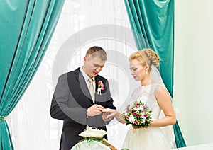 Groom slipping ring on finger of bride at wedding