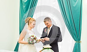 Groom slipping ring on finger of bride at wedding