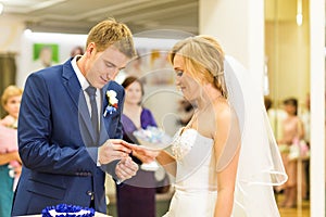 Groom slipping ring on finger of bride at wedding