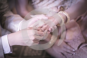 Groom slipping ring on finger of bride in wedding ceremony.