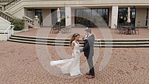 Groom spinning bride outside a wedding venue. 4K 24FPS.