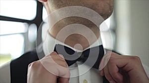 The groom straightens tie bow tie