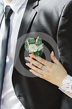 The groom in a suit in a tie and with a buttonhole lit by the rays of the sun