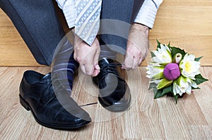 Groom in suit tying shoes