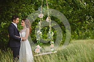 Groom swings the bride on a swing in outdoor park