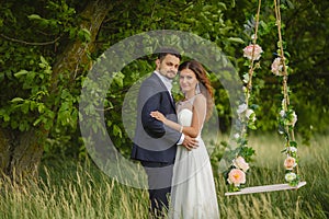 Groom swings the bride on a swing in outdoor park