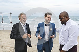 A groom talking to his groomsmen at the beach photo