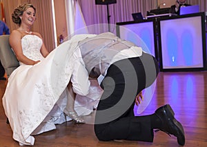 Groom under brides dress taking off garter photo