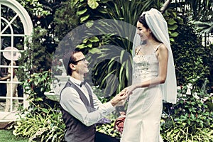 Groom wears the bride`s ring in garden.