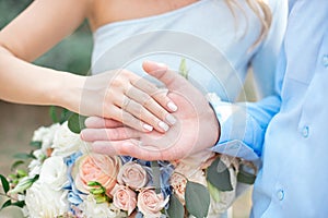 Groom wears bride a wedding ring Bride hand holds a beautiful wedding bouquet.