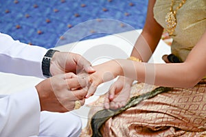 Groom wears a diamond ring onto the brides hand