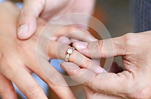 Groom wears ring on bride`s finger. Selective focus at wedding ring