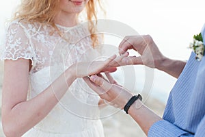 The groom wears a wedding ring on the finger of the bride close-up