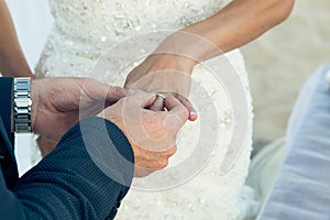 The groom wears a wedding ring on the finger of the bride close-up