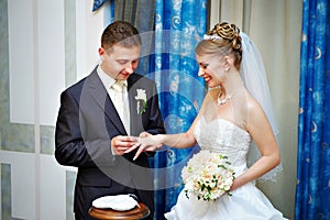 Groom wears wedding ring happy bride