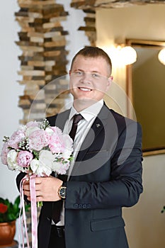 Groom at wedding tuxedo smiling and waiting for bride in the hall of the hotel . Rich groom at wedding day. Elegant groom in costu
